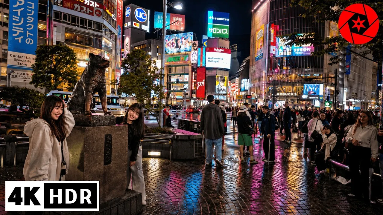 Shibuya at night, with rain-slick streets and a crowd beneath bright signs